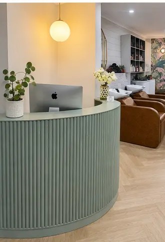 Sage green fluted reception desk under a glowing pendant