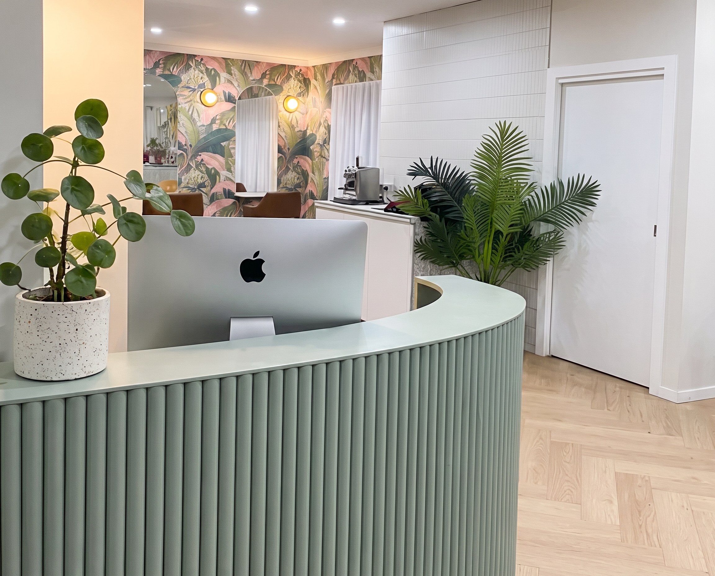Reception desk with iMac and greenery at Arlo & Co