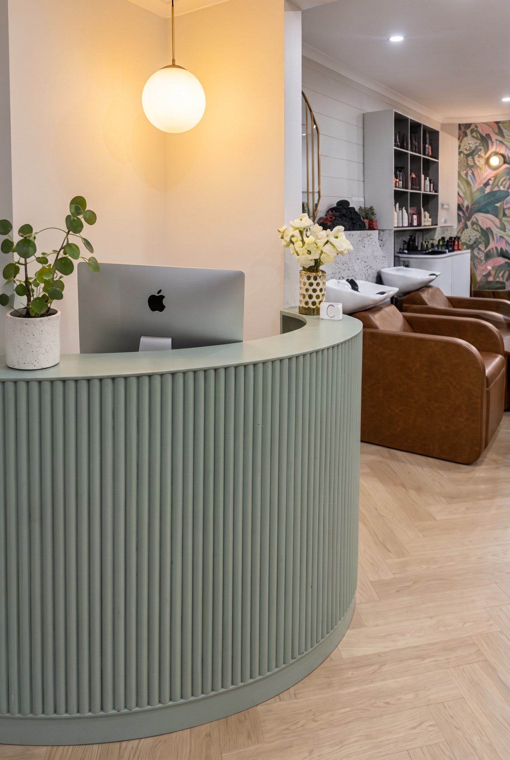 Sage green fluted reception desk under a glowing pendant